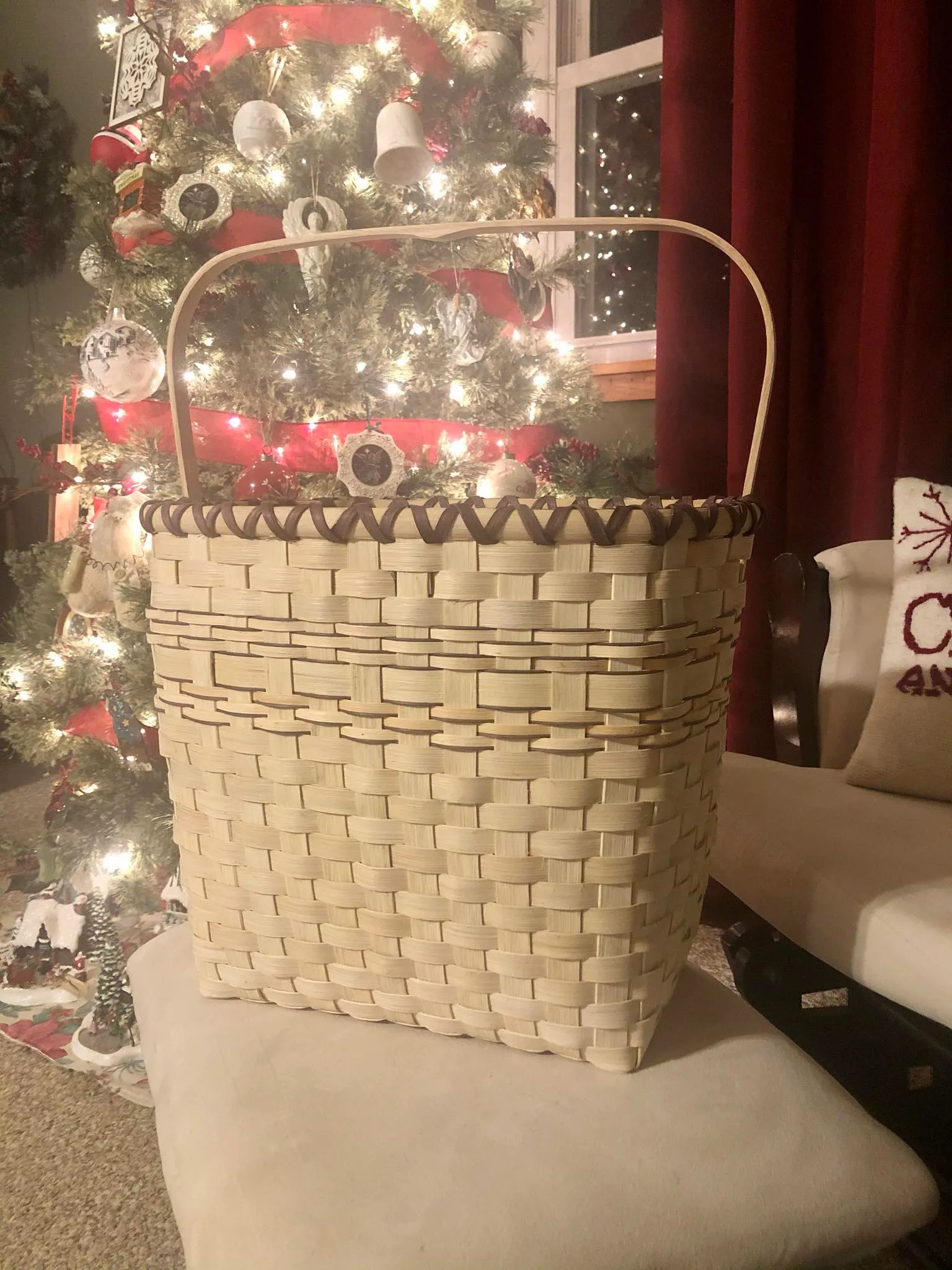 Finished tall rectangular basket with a dark-accented rim and swing handle, beside a decorated Christmas tree.